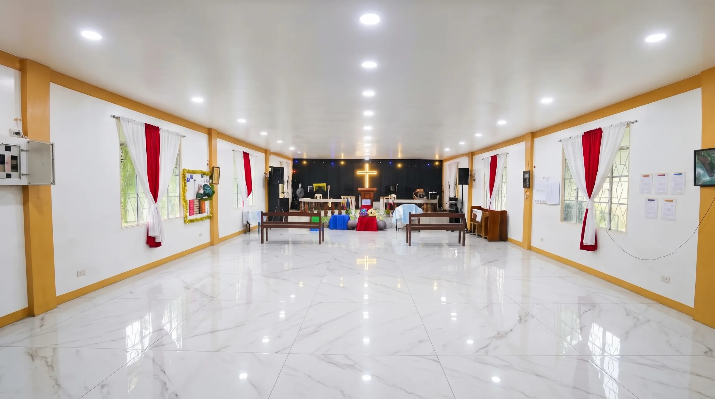 The PCVCCI sanctuary hall with rows of chairs facing the stage and illuminated cross before a service