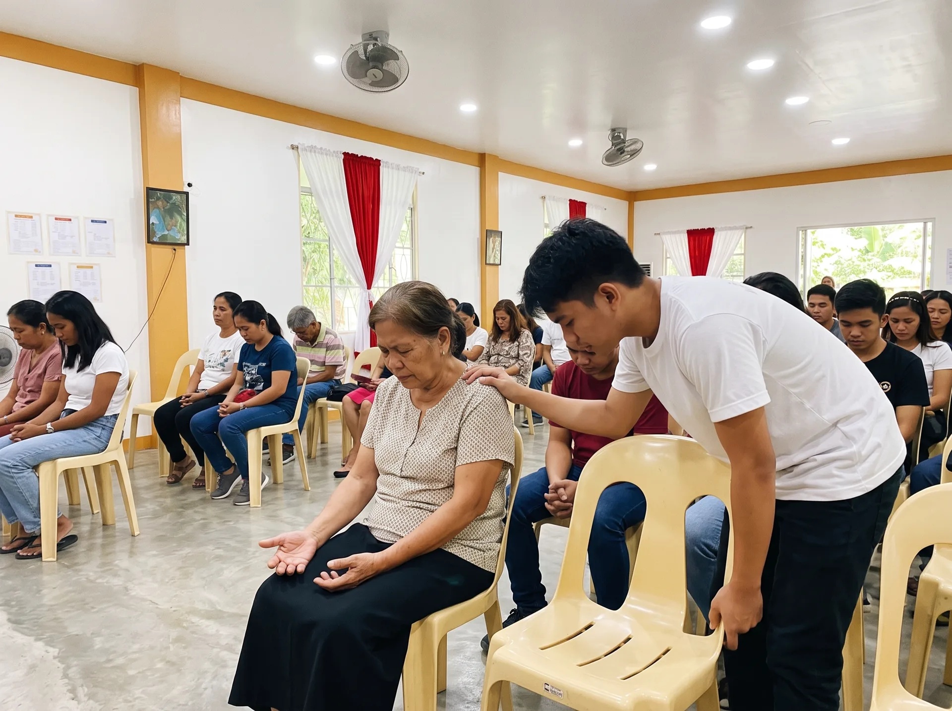 A young man praying with an older woman seated in the PCVCCI sanctuary during ministry time